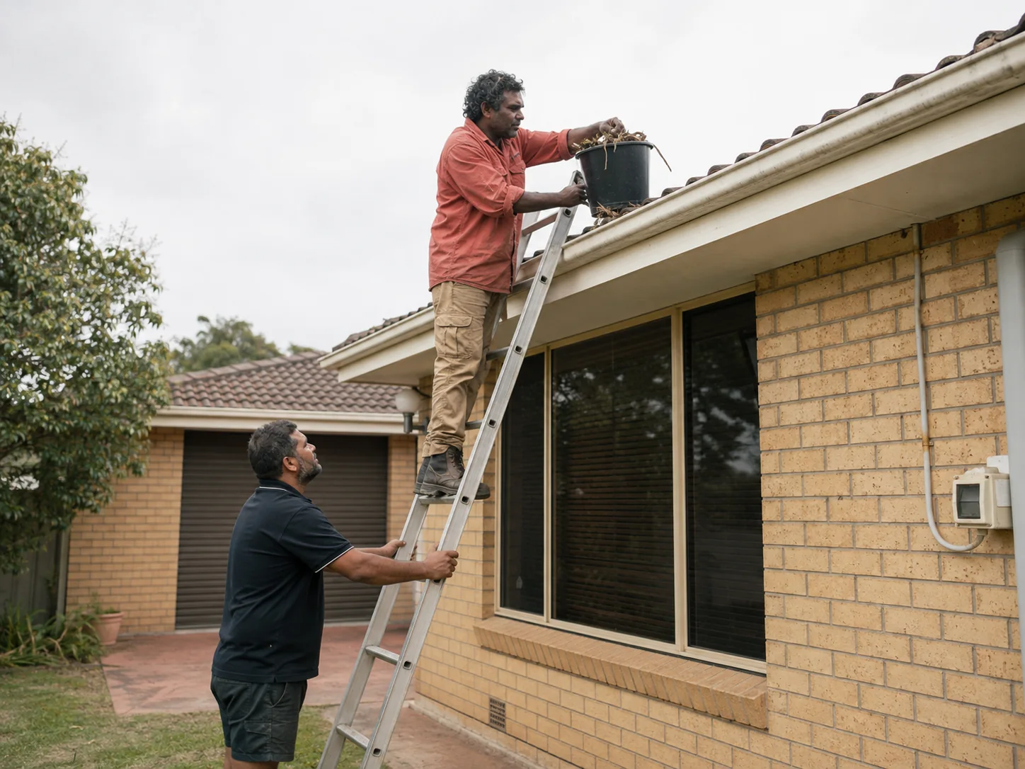 Team clearing leaves from residential gutters