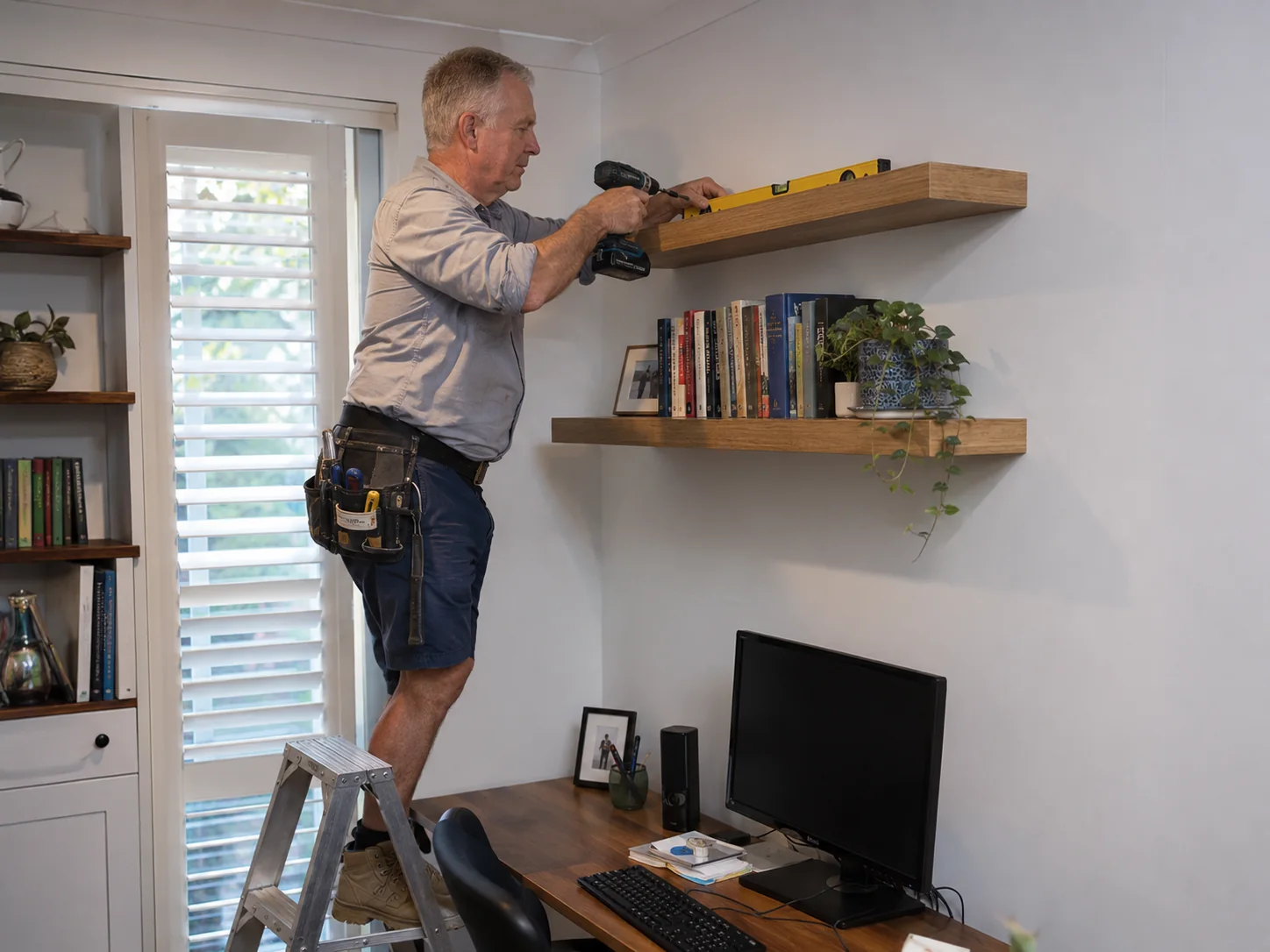 Handyman installing a shelf in a home office
